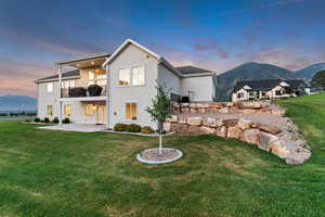 Rear view of property featuring a balcony, a patio, stucco siding, and a mountain view
