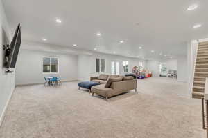 Carpeted living room with recessed lighting, stairway, and healthy amount of natural light