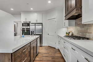 Kitchen with stainless steel appliances, white cabinets, dark wood-style floors, recessed lighting, and backsplash