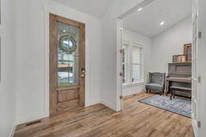 Entrance foyer with vaulted ceiling, light wood-type flooring, and plenty of natural light