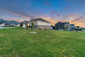 View of side of property with a playground, a yard, stone siding, and a residential view
