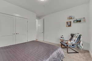 Carpeted bedroom featuring baseboards and a closet
