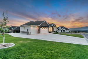 View of front of home featuring stone siding, a garage, a front yard, and concrete driveway