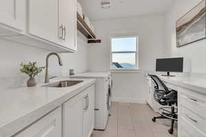 Laundry area with washing machine and clothes dryer, cabinet space, light tile patterned flooring, and an office area