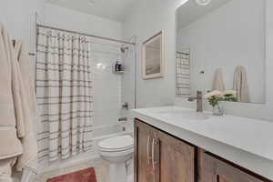 Full bath featuring vanity, shower / tub combo with curtain, and tile patterned floors