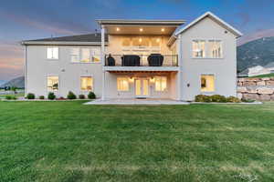 Back of house featuring a patio, stucco siding, a yard, and a balcony