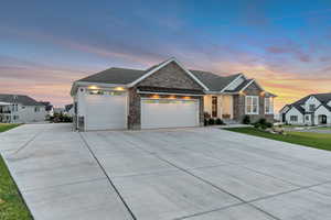 View of front facade with stone siding, an attached garage, concrete driveway, a standing seam roof, and a metal roof