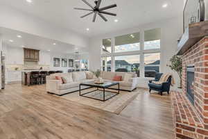 Living area with ceiling fan, a fireplace, light wood-style floors, and recessed lighting