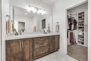 Bathroom featuring double vanity and a walk in closet