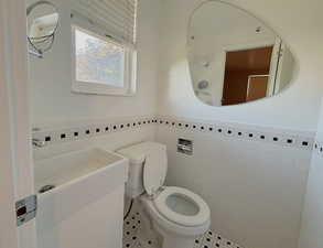 Half bath featuring tile walls, wainscoting, and tile patterned floors
