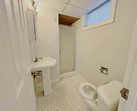 Bathroom with a shower stall, a drop ceiling, and tile patterned floors