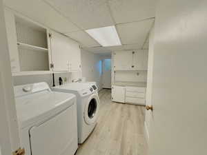 Washroom with cabinet space, independent washer and dryer, and light wood-type flooring