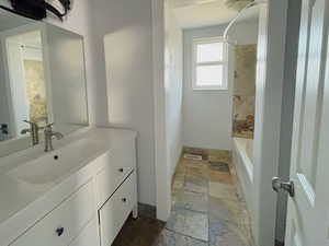 Full bathroom featuring stone tile floors, vanity, and shower / bath combination