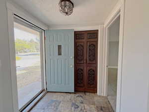 Foyer with a textured ceiling and light stone finish floors