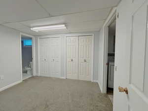 Unfurnished bedroom with multiple closets, carpet floors, washer / clothes dryer, ensuite bathroom, and a drop ceiling