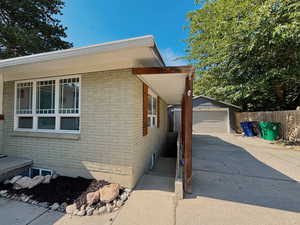 View of property exterior featuring brick siding, concrete driveway, a detached garage, and an outdoor structure