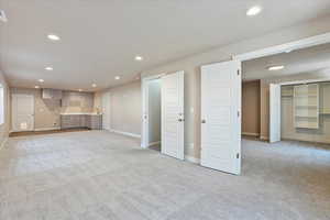 Unfurnished living room with light colored carpet and recessed lighting