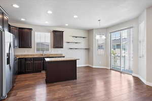 Kitchen with stainless steel fridge with ice dispenser, a center island, dark brown cabinetry, dark wood finished floors, and recessed lighting