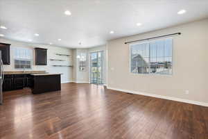 Kitchen with a center island, light countertops, dark wood-style flooring, recessed lighting, and open floor plan