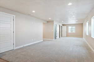 Spare room featuring a textured ceiling, recessed lighting, and light colored carpet