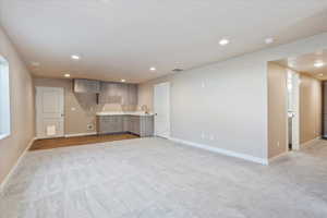 Unfurnished living room with light colored carpet and recessed lighting