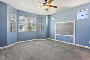 Carpeted empty room with ceiling fan and baseboards