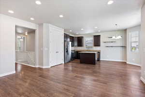 Kitchen with stainless steel fridge, dark brown cabinetry, stove, a center island, and dark wood-type flooring
