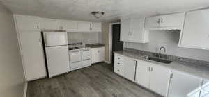 Kitchen featuring white appliances, dark wood-style floors, tasteful backsplash, white cabinets, and a textured ceiling
