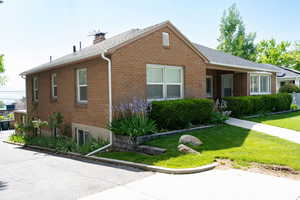 Single story home featuring brick siding, a front yard, a chimney, and a shingled roof