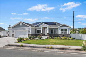 Craftsman-style house with stone siding, solar panels, concrete driveway, a garage, and board and batten siding