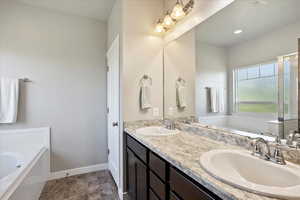 Bathroom with a garden tub, double vanity, and stone finish flooring