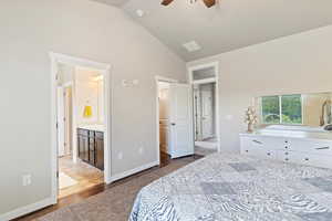 Bedroom featuring dark wood-style flooring, ensuite bathroom, high vaulted ceiling, and ceiling fan