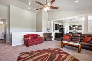 Living area featuring carpet flooring, high vaulted ceiling, ceiling fan, recessed lighting, and decorative columns