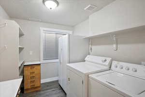 Laundry area with washer and dryer, dark wood finished floors, and a textured ceiling