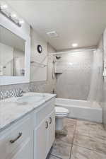 Full bathroom with vanity, shower / bathtub combination with curtain, a textured ceiling, and decorative backsplash