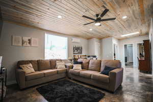 Living room with finished concrete flooring, wood ceiling, a ceiling fan, recessed lighting, and a wall mounted AC