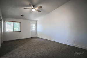 Spare room with ceiling fan, lofted ceiling, and dark carpet