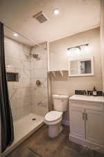 Bathroom featuring vanity, tiled shower, wood finished floors, and recessed lighting