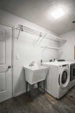 Laundry area featuring dark wood-type flooring, washing machine and clothes dryer, and a textured ceiling