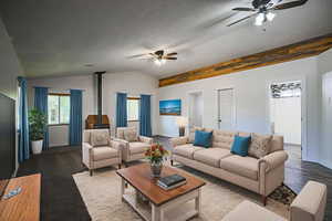 Living room featuring a ceiling fan, a wood stove, and lofted ceiling