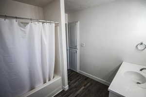 Full bathroom featuring wood finished floors, vanity, shower / bath combo, and a textured ceiling