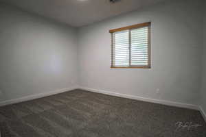 Empty room with dark colored carpet and baseboards