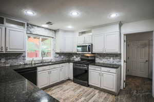 Kitchen featuring gas range oven, black dishwasher, stainless steel microwave, a textured ceiling, and decorative backsplash