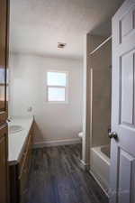 Bathroom featuring vanity, wood finished floors, a textured ceiling, and shower / tub combination