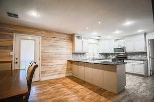 Kitchen featuring stainless steel appliances, a peninsula, light wood finished floors, white cabinetry, and recessed lighting