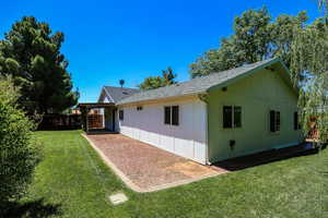 Back of house with a shingled roof and a patio area