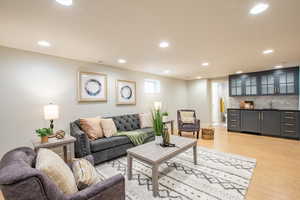Living room with bar with sink, cork flooring, and recessed lighting