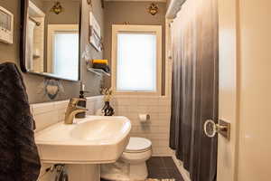 Main level bathroom featuring tile patterned flooring and tile walls
