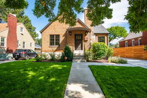 View of front of property featuring brick siding, a chimney, and roof with shingles