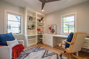 Main level bedroom/office area with light wood-style flooring, healthy amount of natural light, built in desk, and recessed lighting